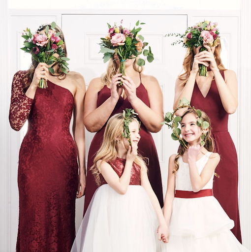 Flower girl dresses in white, one with a red band and one with red lace